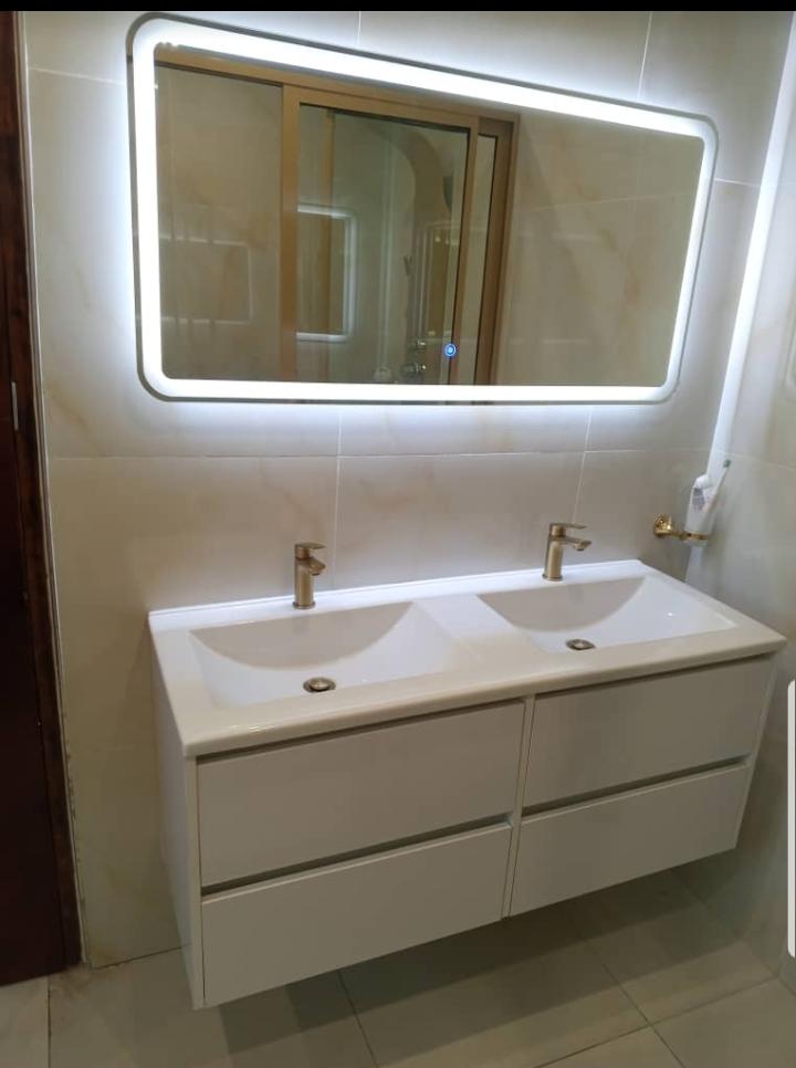 Modern double-sink bathroom vanity with gold faucets and LED mirror