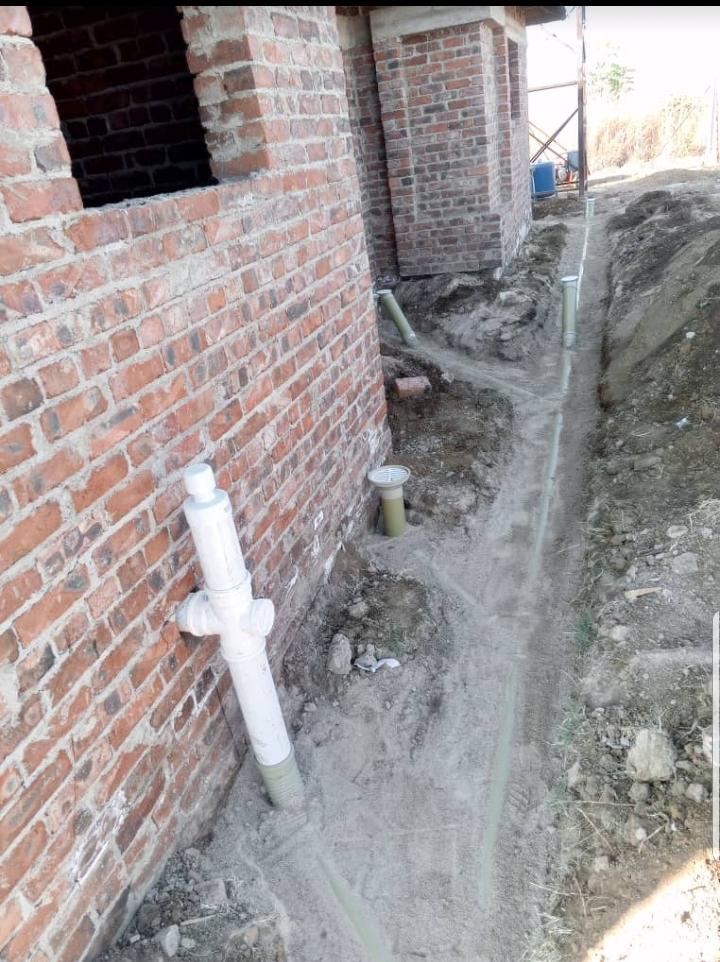 Exterior plumbing installation along a brick building foundation