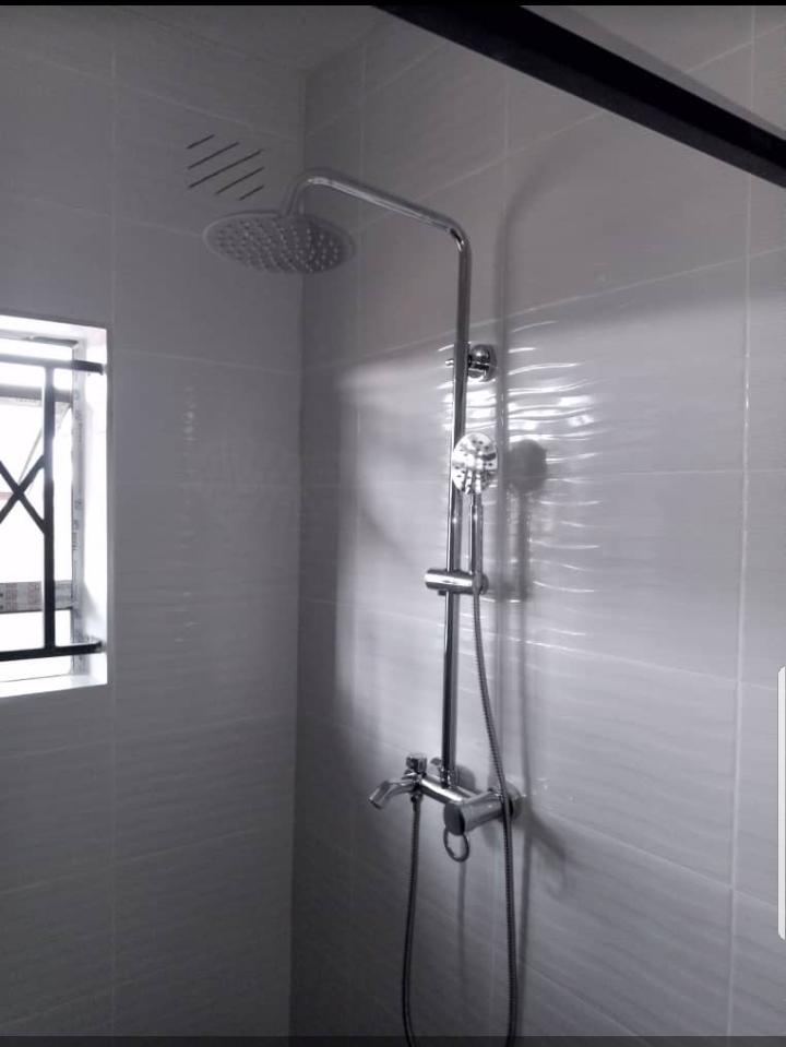 Chrome rain shower system installed in a tiled bathroom